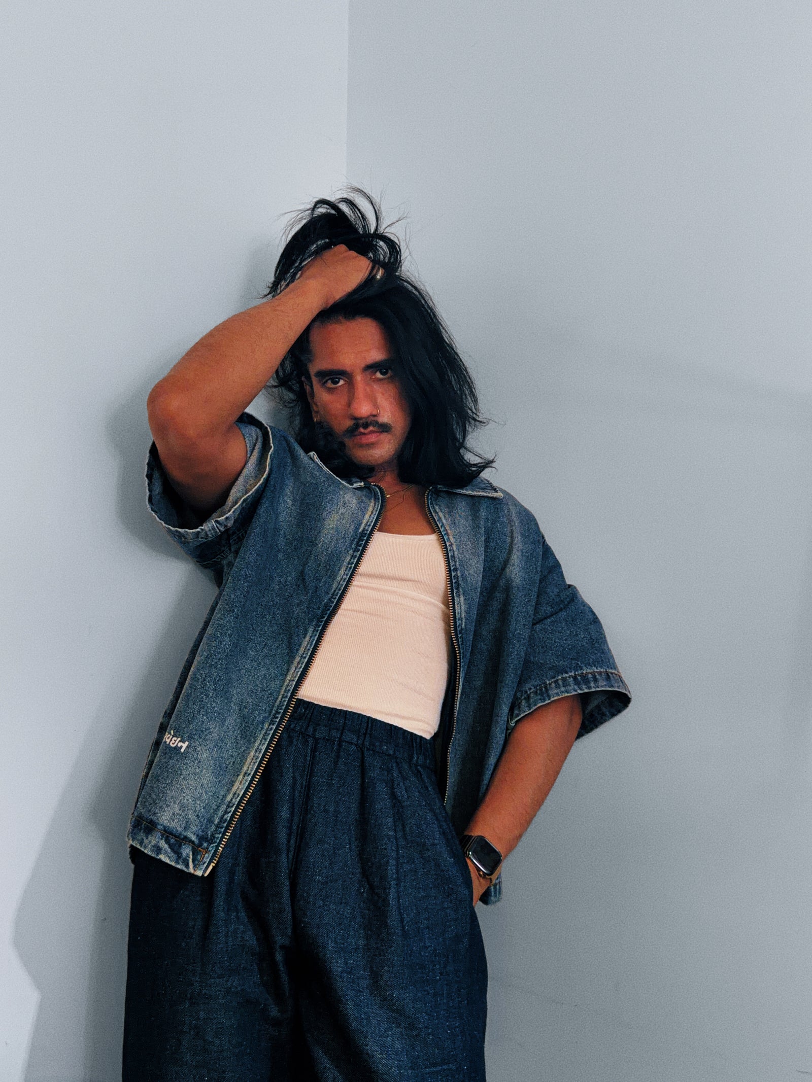 Aarvein campaign styling with an open denim shirt, white tank, and dark trousers